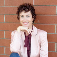A smiling, well-dressed woman with dark curly hair